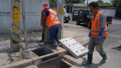 Dos empleados de la alcaldía inspeccionan la ciudad para ir colocando tapaderas.