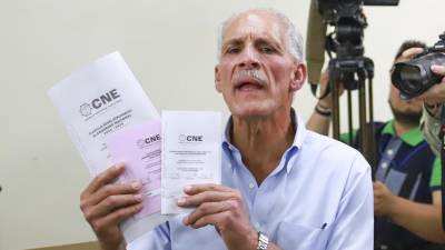 El candidato a la Presidencia de Honduras por el Partido Nacional, Nasry Asfura, muestra papeletas electorales antes de su de votación el domingo, en Tegucigalpa.