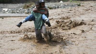 Dos haitianos tratan de cruzar las embravecidas aguas del río La Digue.
