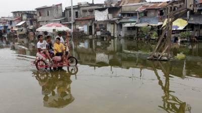 FRM05. MANILA (FILIPINAS), 11/10/2013.- Un grupo de residentes filipinos avanzan por una calle inundada hoy, viernes 11 de octubre de 2013, en la ciudad de Navotas, al norte de Manila (Filipinas). Según la Administración de Servicios Atmosféricos, Geofísicos y Astronómicos de Filipinas, la isla de Luzon está bajo alerta de tifón debido a que el tifón Nari se fortaleció y se aproxima a Filipinas. EFE/FRANCIS R. MALASIG