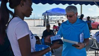 Empleados del aeropuerto de Freeport revisan los documentos de los bahameños que viajan hacia EEUU para verificar si poseen visa./AFP.