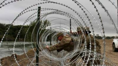 Militares estadounidenses retiran el alambrado que instalaron en Laredo para evitar el ingreso de migrantes./AFP.