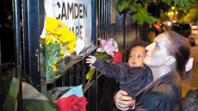 Eva Caine, right, and her 10-month-old granddaughter Ama stand near flowers on a road sign opposite the home of British singer Amy Winehouse in Camden Square, London, following her death, Saturday, July 23, 2011. The singer was found dead Saturday by ambulance crews called to her home in north London's Camden area, a youth-culture mecca known for its music scene, its pubs, and the availability of illegal drugs. (AP Photo/Joel Ryan)