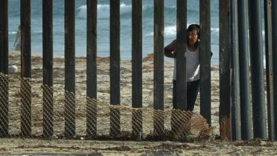 Un hombre mira hacia los Estados Unidos desde el lado mexicano de la valla fronteriza que divide a los dos países en San Diego, California. AFP