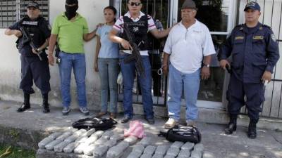 Los sospechosos junto a la droga decomisada.