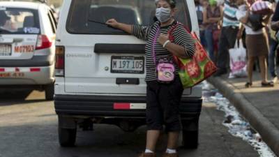 Una mujer con tapabocas espera un bus en una calle de Managua (Nicaragua). EFE