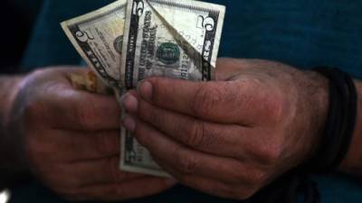 A deported undocumented Honduran man prepares to change US dollar bills upon his arrival from the US at Ramon Villeda Morales airport in San Pedro Sula, Honduras on September 27, 2019. - Three planes transporting undocumented Hondurans arrived from the US in San Pedro Sula Friday. US President Donald Trump and Honduran President Juan Orlando Hernandez signed a controversial agreement to reduce migration. (Photo by ORLANDO SIERRA / AFP)