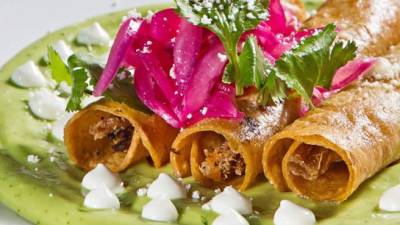 Para servir, agregar la salsa de aguacate a las flautas y se añade crema ácida y queso doble crema.