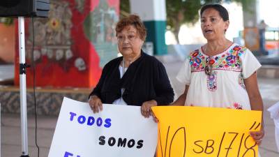 Un par de activistas al protestar contra la ley antiinmigrante SB 1718 de Florida.