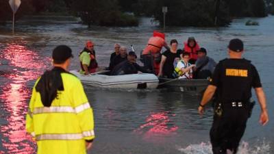 People are rescued from a hotel by boat after Hurricane Harvey caused heavy flooding in Houston, Texas on August 27, 2017. Massive flooding unleashed by deadly monster storm Harvey left Houston -- the fourth-largest city in the United States -- increasingly isolated as its airports and highways shut down and residents fled homes waist-deep in water. / AFP PHOTO / MARK RALSTON