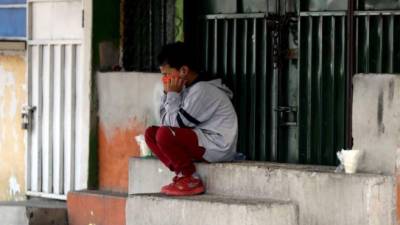 Un niño con tapabocas descansa este viernes en una acera de Tegucigalpa.