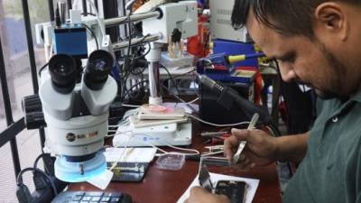 Equipo. Un técnico mientras repara un celular con problemas de placa. Foto: Amilcar Izaguirre.