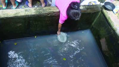 Hondureña recogiendo agua de una pila | Fotografía de archivo