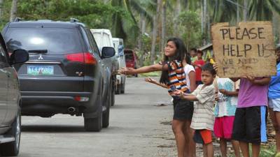 Imagen facilitada hoy, martes 12 de noviembre de 2013 de varios niños que pide ayudan a los coches que pasan en una zona devastada por el paso tifón Haiyan en la localidad de Borbon, en la provincia de Cebu (Filipinas) ayer .