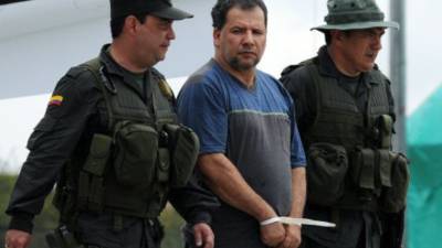 Daniel Rendon Herrera (C), a.k.a. 'Don Mario', is escorted by police officers on April 15, 2009 in Bogota, Colombia. Rendon Herrera, Colombia's biggest drug kingpin for whom the government had offered a 2.1-million-dollar bounty, was arrested by a special unit of 315 police in Antioquia Department. TOPSHOTS/AFP PHOTO/Rodrigo Arangua