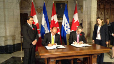 Los ministros de Comercio de Honduras, Adonis Lavaire, y de Canadá, Ed Fast, durante la firma del documento.