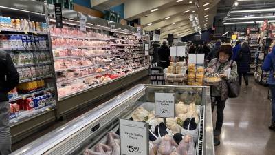Una mujer toma una tarta frente a un congelador lleno de pavos naturales y orgánicos en un supermercado en Washington.