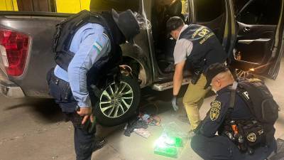 Policías inspeccionan vehículo que llevaba 15 kilos de cocaína en un compartimento falso, en Corinto, frontera de Honduras con Guatemala.