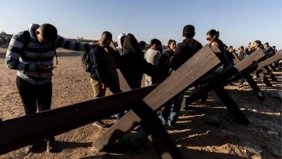 Migrantes esperan a ser procesados por agentes de la Patrulla Fronteriza de Estados Unidos tras cruzar ilegalmente en EE.UU., en Yuma, Arizona.