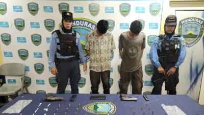 Miembros de la Policía Nacional presentan a los dos supuestos gatilleros de la MS-13 con las evidencias decomisadas en la escena.