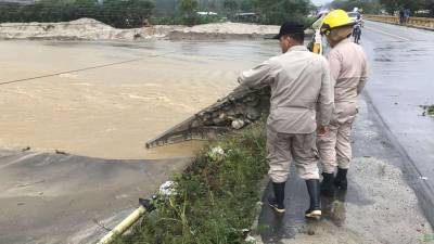 Dos bomberos supervisan los daños provocados por lluvias en Omoa, Cortés.