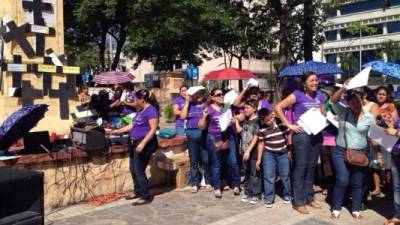 Las mujeres colocan cruces negras en el parque central de San Pedro Sula por la ola de muertes.