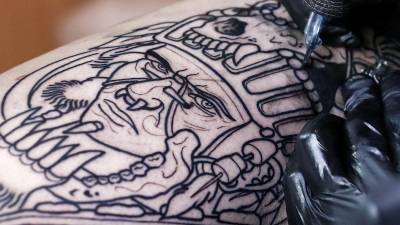 Una persona se tatúa un dibujo con tinta negra en una pierna.