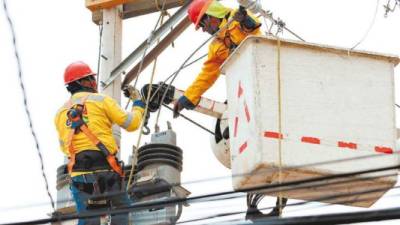 Dos empleados de la EEH trabajan en las líneas de transmisión de energía.