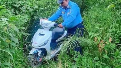 Un agente de la Policía traslada la moto que estaba siendo desmantelada.