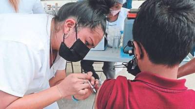 Enfermera hondureña aplica vacuna a un menor de edad.