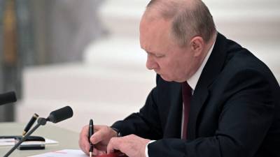 El presidente ruso Vladimir Putin firma documentos, incluido un decreto que reconoce como independientes a dos regiones separatistas respaldadas por Rusia en el este de Ucrania, durante una ceremonia en el Kremlin en Moscú.