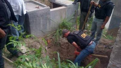 Personal de la DNIC excava una fosa común en el patio de una casa allanada.