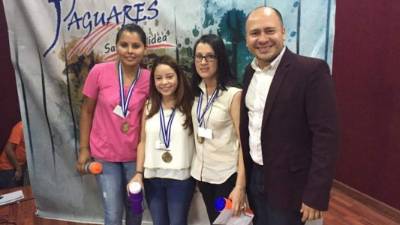 Las tres estudiantes que integraron el equipo de We Watch Day Care posan con sus medallas.
