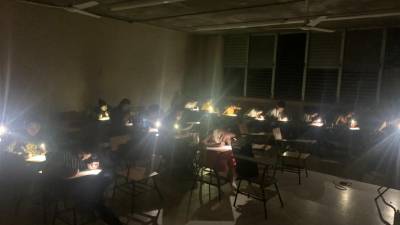 Estudiantes de la clase de Géneros Periodísticos en Unah-vs, realizan su examen con la luz de sus celulares.