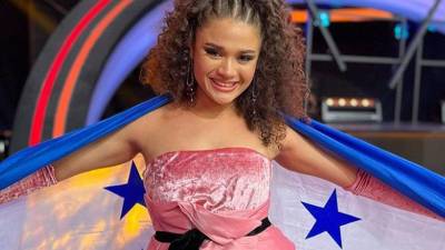 La cantante Cesia Sáenz posa junto a la Bandera de Honduras.