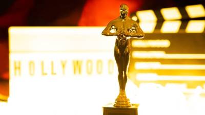 Un premio Oscar con un fondo en el que se muestra una claqueta y un rótulo con la leyenda Hollywood. Imagen de referencia.