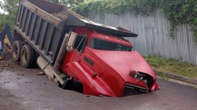 Volqueta roja dentro de un socavón en Lomas del Guijarro, Tegucigalpa.