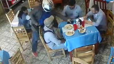 Uno de los asaltantes toma los celulares que los clientes pusieron en la mesa para que se los llevara.