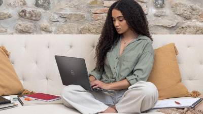 Mujer sentada en un sofá rodeada de cuadernos y con su laptop Dell en el regazo, Dell ofrece laptops según tus necesidades y presupuesto. Busca la asesoría de los Laptop Masters de Jetstereo para hacer tu mejor elección.