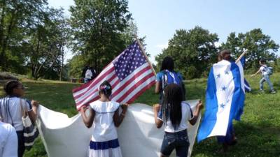 Niños de Honduras en Estados Unidos ondean las banderas de ambos países en un parque de Nueva York.