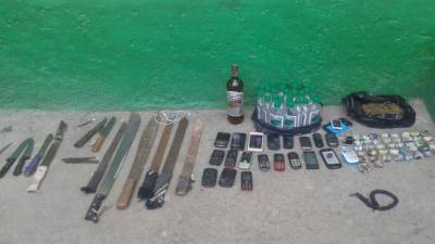 Parte de las armas, alcohol y celulares encontradas en el interior del Centro Penal Sampedrano.