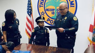 Fotografía cedida por la Policía de Miami que muestra al niño Daniel DJ mientras posa con miembros del departamento de Policía de la ciudad.