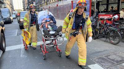 Bomberos trasladan a uno de los cuatro heridos tras el derrumbe de un edificio de parqueo.