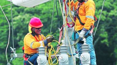 Dos técnicos de la Empresa Energía Honduras realizan labores de instalación de transformadores.