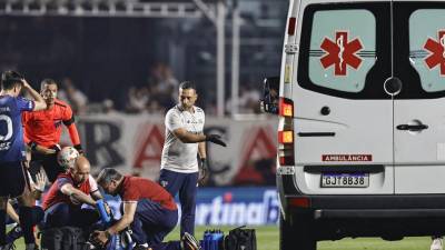Juan Izquierdo (abajo) de Nacional es atendido por personal de la salud .