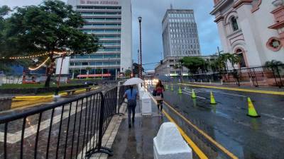 Dos mujeres se cubren de la lluvia en el centro de San Pedro Sula.