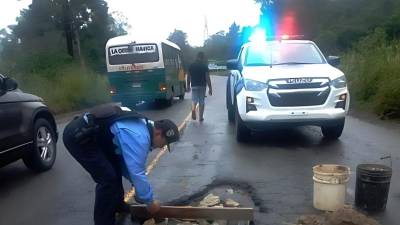Policías del departamento de Atlántida se han dado a la tarea de apoyar la labor de tapar los enormes baches que hay en la carretera CA-13.