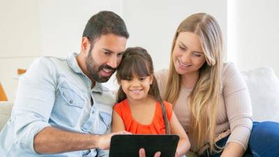 Dos adultos muestran a su hija como utilizar las herramientas digitales sin caer en riesgos.