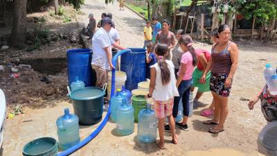 Pobladores de Copán Ruinas llenan baldes y botellones con agua entregada en carros cisterna para abastecer sus hogares.