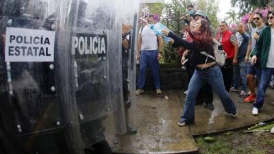 Personas se enfrentan con integrantes de la policía antimotines este domingo en Guadalajara.